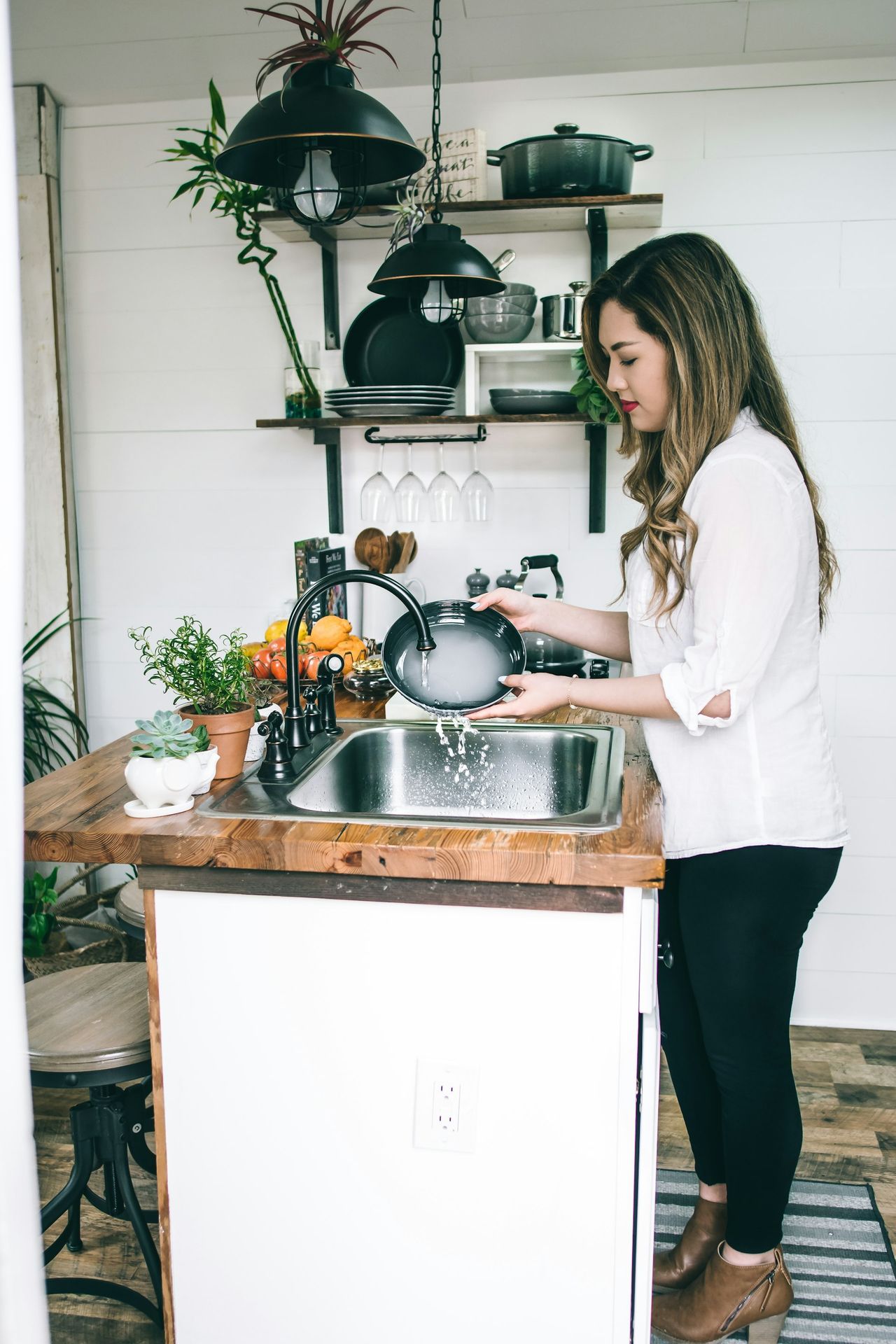 woman wearing white blouse washing dish on the faucet